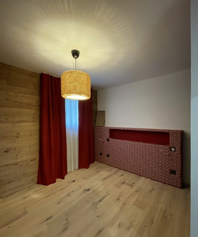 Chambre moderne avec lit intégré dans alcôve murale, revêtement bois naturel au mur et sol parquet chêne