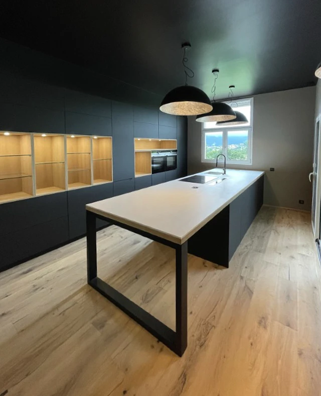 Cuisine moderne avec îlot central équipé d'un évier, plan de travail blanc et structure métallique noire