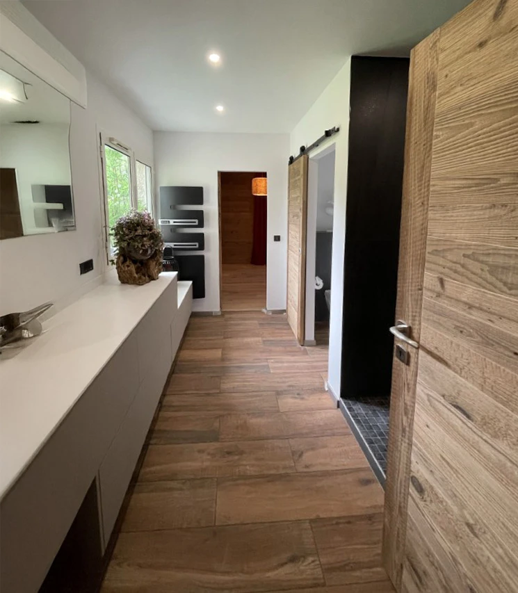 Intérieur moderne d'un couloir résidentiel avec parquet en bois massif, meubles suspendus blancs laqués, éclairage LED encastré au plafond