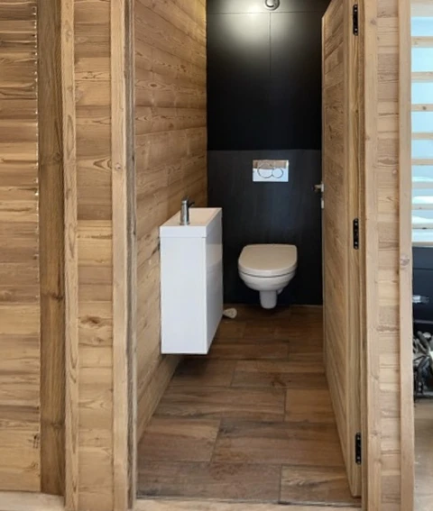 Toilettes modernes dans espace résidentiel avec murs en lambris bois naturel