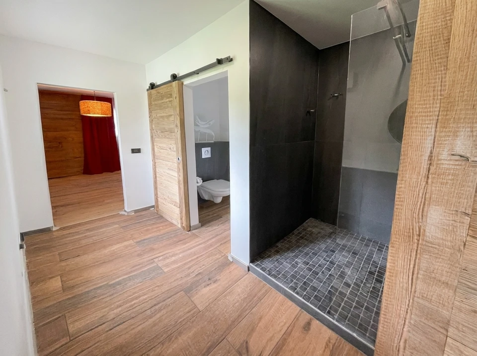 Intérieur de salle de bain en rénovation avec ouvrier appliquant du joint sur carrelage mosaïque